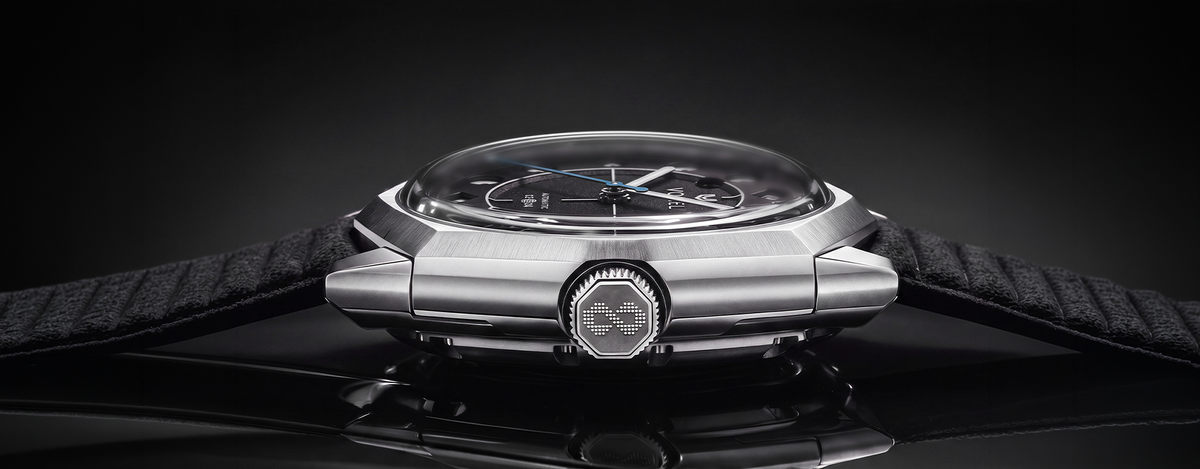 Side view of a VOXEL steel watch showing its domed crystal, octagonal crown with logo and black textured fabric strap