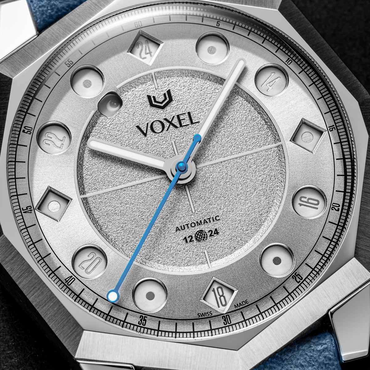 Close-up of the VOXEL Meridion Silver Star Dial showing the 12/24 jumping-hours display in 24-hour mode, textured silver centre and blue seconds hand
