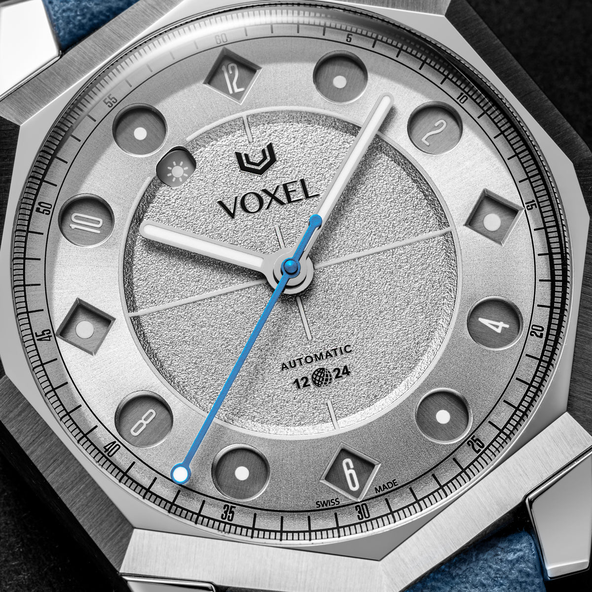 Close-up of the VOXEL Meridion Silver Star Dial showing the 12/24 jumping-hours display in 12-hour mode, textured silver centre and blue seconds hand