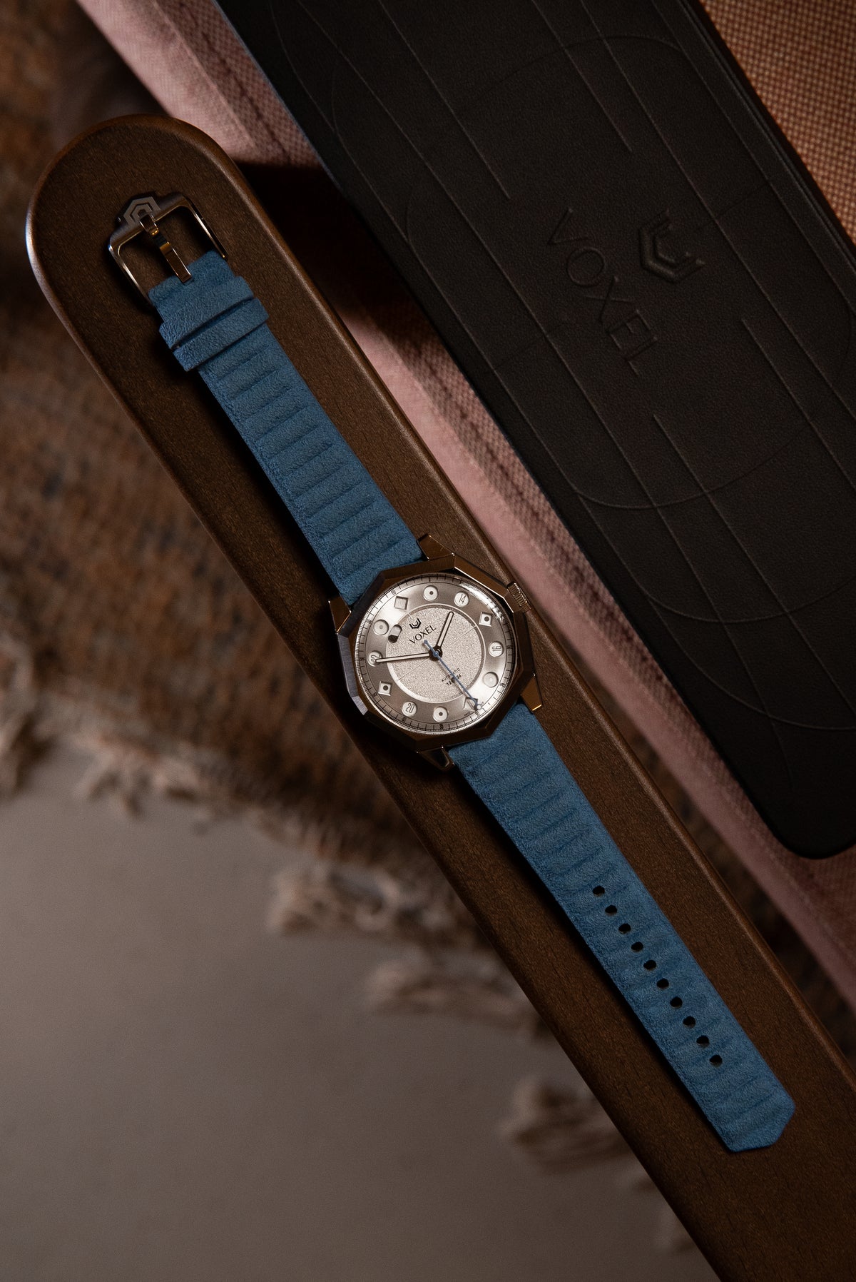 VOXEL watch with silver textured dial and blue fabric strap, resting beside its black presentation box